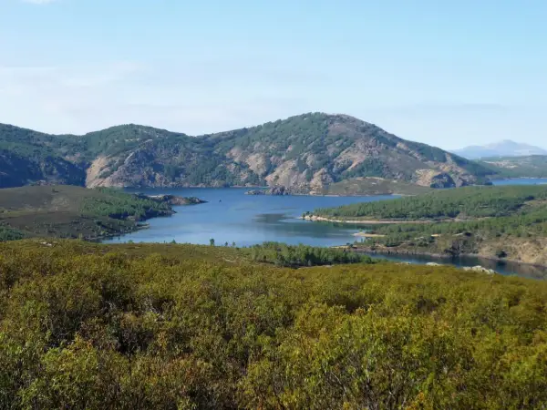 Paisaje sereno con un embalse azul rodeado de montañas verdes. La senda del Genaro se adentra en este idílico entorno natural.