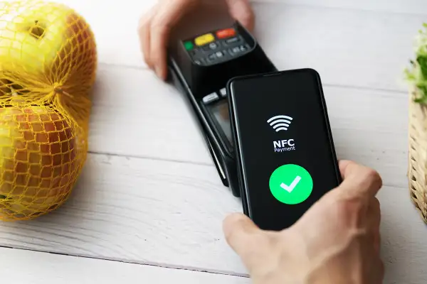 Płatność zbliżeniowa telefonem. Ekran pokazuje "NFC Payment" i zielony znaczek. Dowiedz się, jak włączyć NFC w telefonie, by płacić wygodnie.