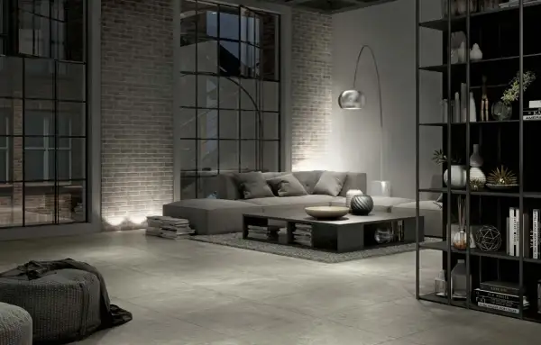 Salon industriel moderne avec canapé gris, table basse, étagères noires et **carrelage rectifié** au sol.