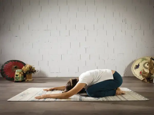 Mujer en postura de niño, buscando el yoga significado espiritual. Relajación y conexión interior.