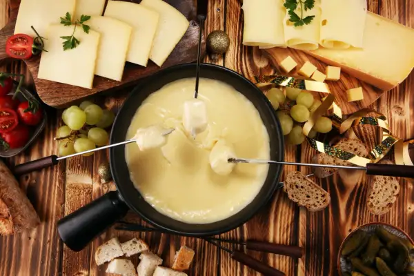 Fondue au fromage, une spécialité Auvergne Rhône Alpes, avec pain, raisins et tomates.