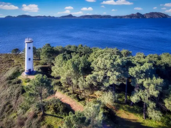 El faro de Cabo Home se alza solitario en una colina verde, vigilando el azul intenso del mar y las islas lejanas.
