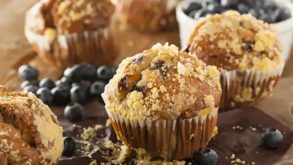 Frisch gebackene Blaubeermuffins mit Streuseln, ein köstliches Muffins Rezept, umgeben von frischen Blaubeeren.