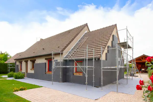 Maison en cours d'isolation par l'extérieur. Les inconvénients sont visibles : échafaudages, accès gêné, et aspect inachevé.