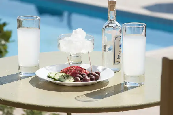 Ouzo, grecki alkohol, podawany z oliwkami i ogórkiem, przy basenie, jak na wakacjach pod Partenonem.