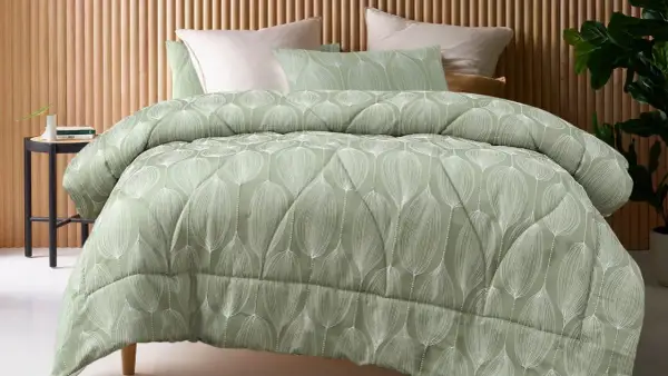 A sage green coverlet with a white leaf pattern. This coverlet serves as a decorative top layer for the bed, adding warmth and style.