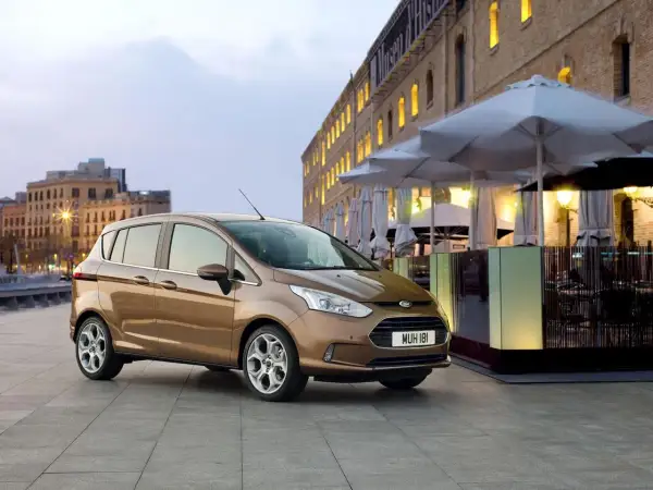 Brązowy Ford B-Max na tle miejskiej zabudowy. Idealny do miasta, jego wymiary sprawiają, że parkowanie to przyjemność.