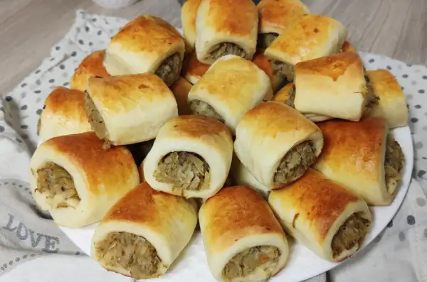 Złociste paszteciki z pieczarkami i kapustą, ułożone na talerzu, kuszą swoim wyglądem i aromatem.