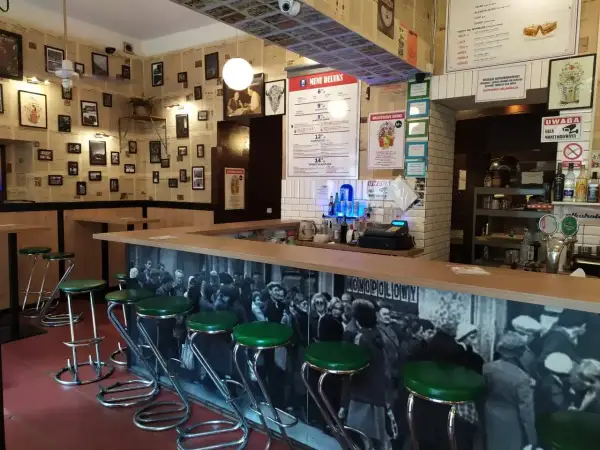 Stylowy bar z zielonymi stołkami i czarno-białą fototapetą. Idealne miejsce, gdzie na drinka w Krakowie.