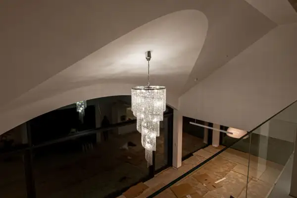 Elegancki zwis do lampy z kryształkami lśni w nowoczesnym wnętrzu z wysokim sufitem.