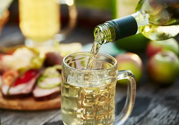 Wino z jabłek 10l nalewane do kufla. Na stole jabłka i przekąski.