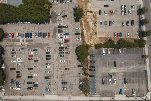 Widok z lotu ptaka na parking, gdzie doszło do kolizji na terenie prywatnym. Widać wiele zaparkowanych samochodów.