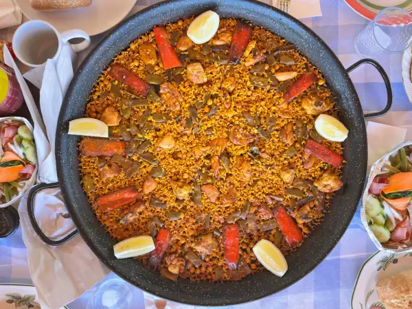 Paella gigante con pollo, judías verdes, pimientos rojos y limón. Los ingredientes paella lucen deliciosos en este plato tradicional español.
