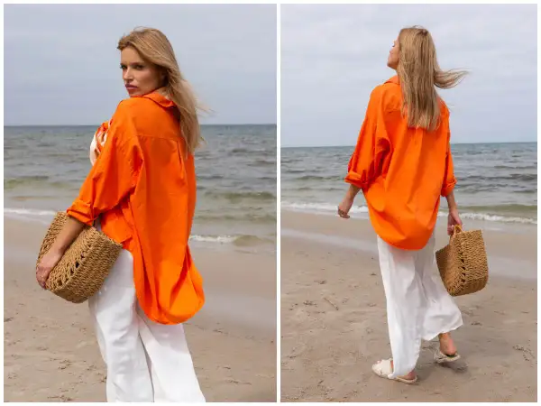 Kobieta w pomarańczowej koszuli i białych spodniach na plaży. Idealne outfity na lato, z plecioną torbą.