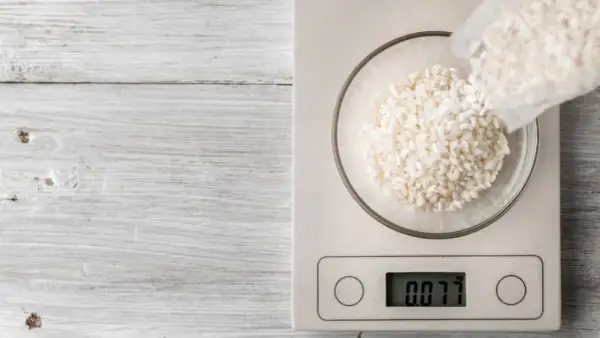 Balanza digital muestra 0.077 kg de arroz en un bol. Ideal para calcular cuánto arroz por persona.