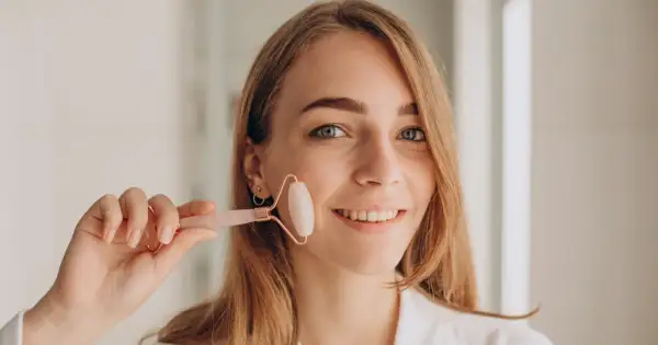 Uśmiechnięta kobieta z blond włosami trzyma różowy roller do twarzy. Zastanawiasz się, jaki roller wybrać? Ten model jest idealny do masażu.