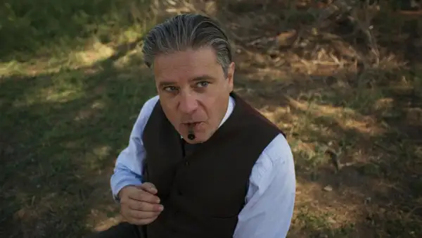Un uomo con un sigaro in bocca, vestito elegantemente, sembra un re.