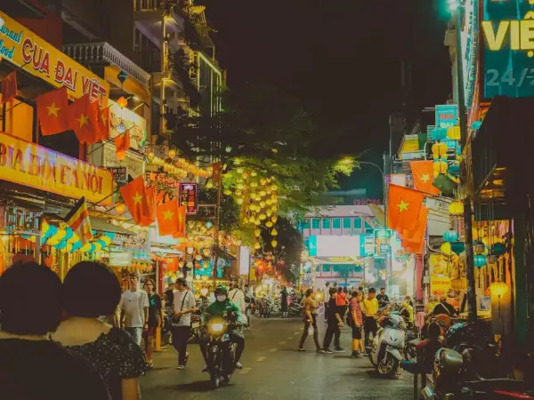 Tętniąca życiem nocą ulica w Ho Chi Minh (miasto), ozdobiona flagami Wietnamu i lampionami.