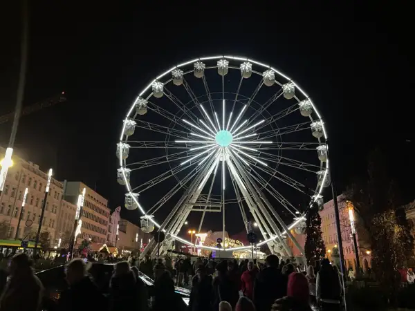 Nocny plac wolności poznań rozświetla ogromne koło widokowe. Tłumy ludzi spacerują wśród świątecznych iluminacji.