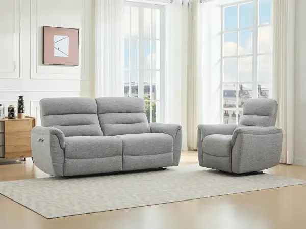 A grey recliner sofa and armchair in a bright living room with large windows.