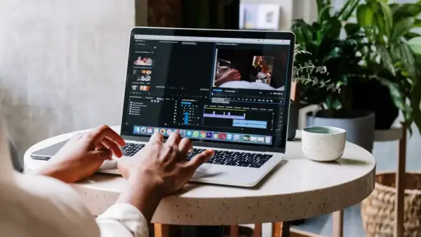 Montażysta filmów pracuje nad projektem na laptopie. Zastanawiasz się, ile zarabia montażysta filmów?