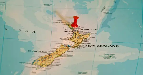 Czerwony pinezka zaznacza Nową Zelandię na mapie. To państwo wyspiarskie, które geograficznie należy do Oceanii, choć kulturowo i politycznie często kojarzone jest z Australią, która leży na kontynencie australijskim.