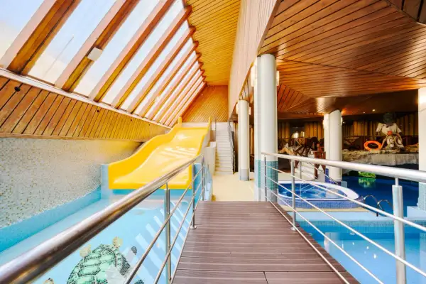 Wodne szaleństwo w hotelu Belvedere Resort & Spa! Żółta zjeżdżalnia wodna i basen z mozaiką żółwi czekają na gości.