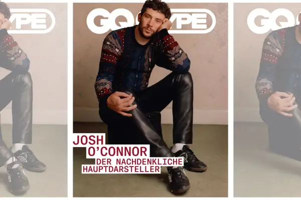 Josh O'Connor, der nachdenkliche Hauptdarsteller, sitzt lässig in Lederhosen und einem gemusterten Pullover.