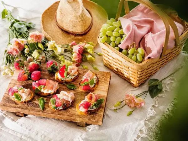 En härlig picknick med bruschetta, jordgubbar, vindruvor i korg och en stråhatt. Perfekt picknick mat för en solig dag.