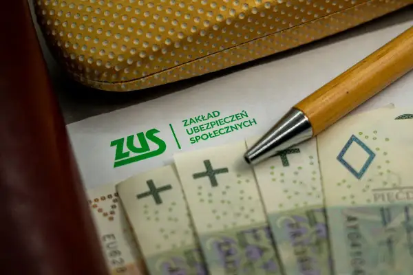 Zwolnienie z ZUS? Na papierze z logo ZUS leżą polskie banknoty i długopis.