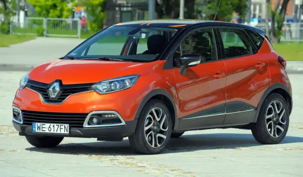 Pomarańczowy Renault Captur 2015 z czarnym dachem i pomarańczowymi akcentami stoi na placu.