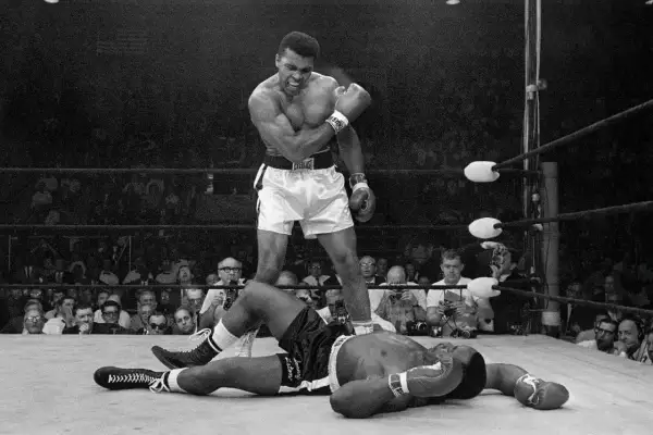 Muhammad Ali stands over a fallen opponent, embodying his famous quote to float like a butterfly and sting like a bee.