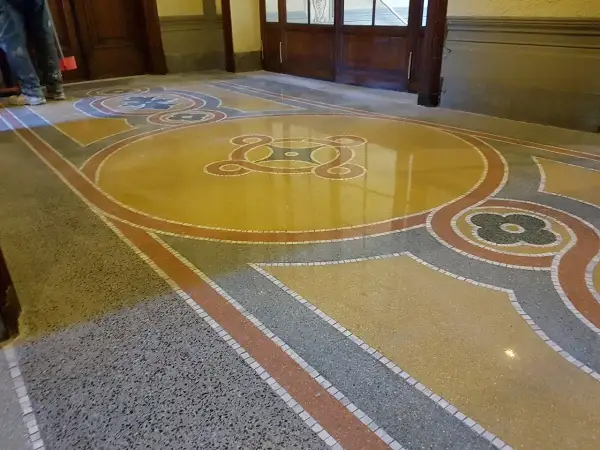 Pavimenti marmo anni 70 con motivi geometrici e floreali in giallo, grigio e rosso. Un restauro che riporta alla luce la bellezza del passato.