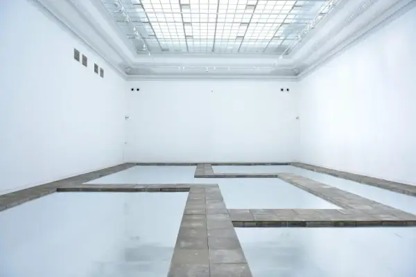 Biała przestrzeń galerii z lustrzaną podłogą i kamiennymi ścieżkami tworzącymi labirynt. Kojący widok, jakbyś spacerował po chmurach.