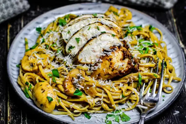 Ein Teller cremiger Pasta mit gebratenem Hähnchen, Pilzen und Parmesan. Dieses Chicken Alfredo Gericht sieht köstlich aus.