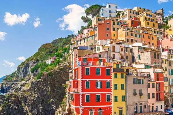 Färgstarka hus klättrar uppför en brant sluttning vid kusten i Italien. En vy som inbjuder till dricks i Italien.