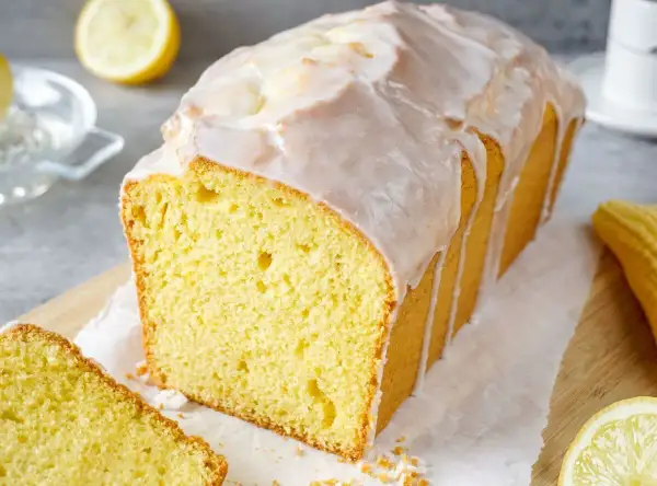 Saftiger Zitronenkuchen mit Zuckerguss, perfekt für Ihr nächstes zitronenkuchen rezept. Ein Stück ist bereits angeschnitten.