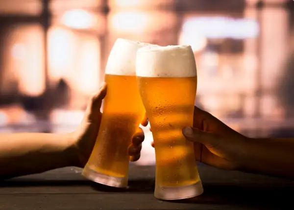 Due mani brindano con due bicchieri di birra ghiacciata, un momento di piacere che celebra la birra proprietà.