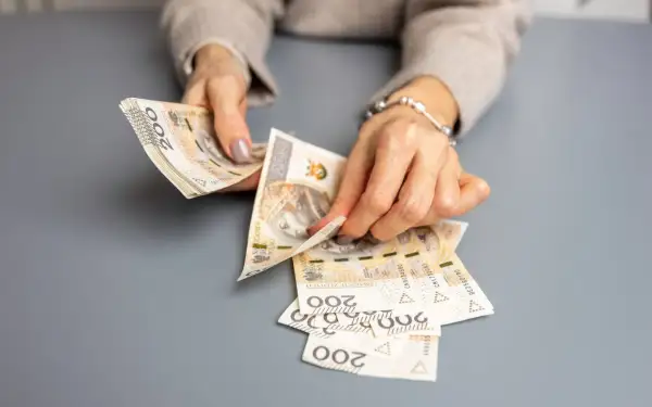 Dłonie liczą banknoty 200 zł, przygotowując świadczenie urlopowe.