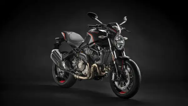 Czarny motocykl Ducati Monster na ciemnym tle.