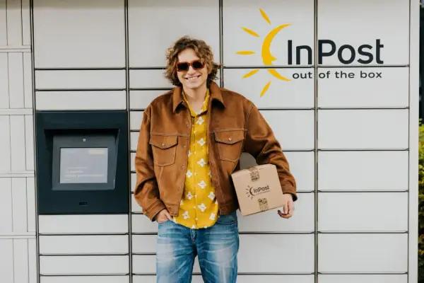 Uśmiechnięty mężczyzna z paczką InPost. Wysłał ją w piątek, więc pewnie dojdzie w poniedziałek.