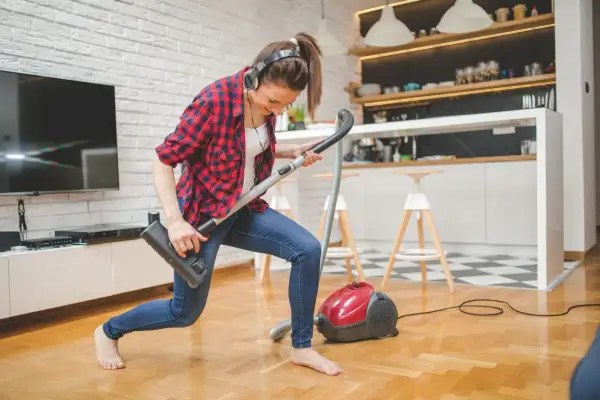 Frau mit Kopfhörern spielt Staubsauger-Gitarre. So macht **family fitness** Spaß!