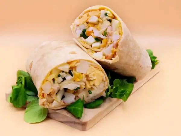 Pyszna tortilla z jajkiem, warzywami i kurczakiem, podana na desce z zieloną sałatą. Idealna na szybki lunch.