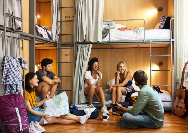 Jóvenes planean su viaje en un hostal, con literas y un ambiente social.