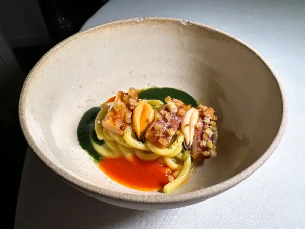 Un piatto di pasta con frutti di mare, salsa verde e rossa, croccantezza e un tocco da ciccio sultano stelle michelin.
