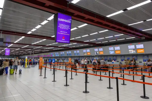 Kasa odpraw na lotnisku Londyn Luton. Pasażerowie z bagażami czekają w kolejce do stanowisk linii lotniczych easyJet.