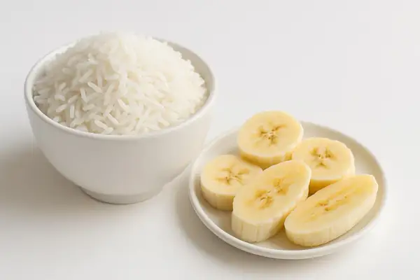 Riso bianco in una ciotola e fette di banana su un piattino, ingredienti ideali per una dieta astringente.