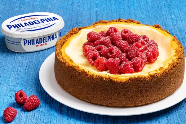 New York cheesecake con lamponi freschi, accanto a un vasetto di Philadelphia Original.