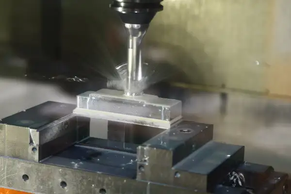 Precyzyjne frezowanie aluminium na maszynie CNC. Chłodziwo rozpryskuje się wokół obrabianego elementu.