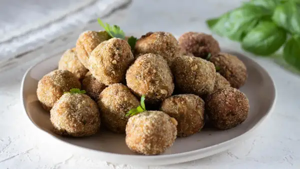 Un piatto colmo di polpette di melanzane, dorate e croccanti, pronte per essere gustate. La ricetta originale che conquista tutti.